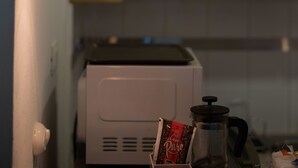A kitchen with a hanging light bulb, a coffee maker, and a packet of coffee. - Escape Apartment in Gazcue Close to Colonial Zone (Santo Domingo)