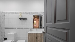 A modern bathroom with a white sink, wooden cabinets, and a geometric tile backsplash. - Escape Apartment in Gazcue Close to Colonial Zone (Santo Domingo)