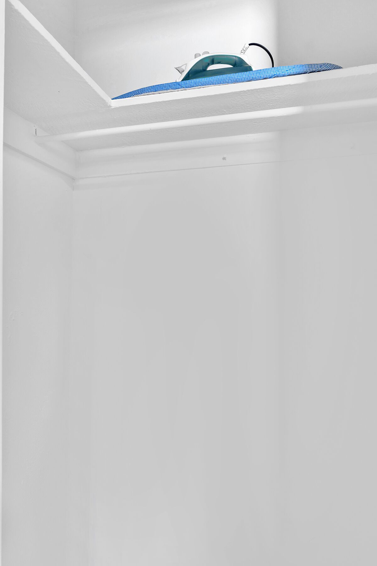 A white room with a sloped ceiling and a visible duct or pipe running across the top.