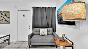 A modern living room with a grey sofa, a wooden coffee table, a small side table, and a large woven lamp.