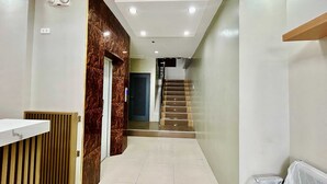 Un intérieur moderne comprenant un comptoir d’accueil, un escalier et un mur à la texture évoquant le marbre.