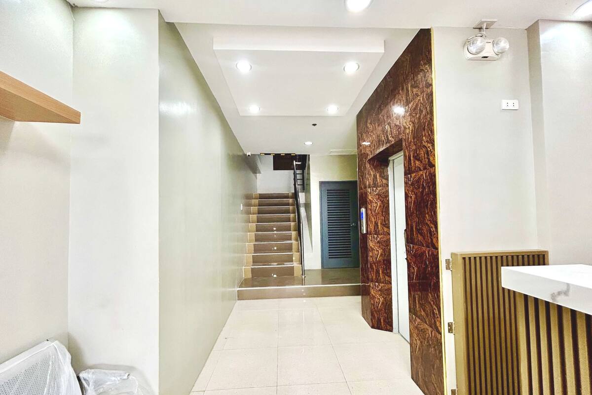 A modern interior with a staircase, a reception desk, and a wall with a wood-like texture.