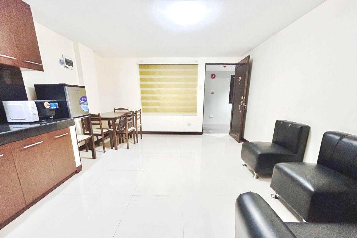 A modern kitchen with a microwave, refrigerator, and dining area with chairs and a table.