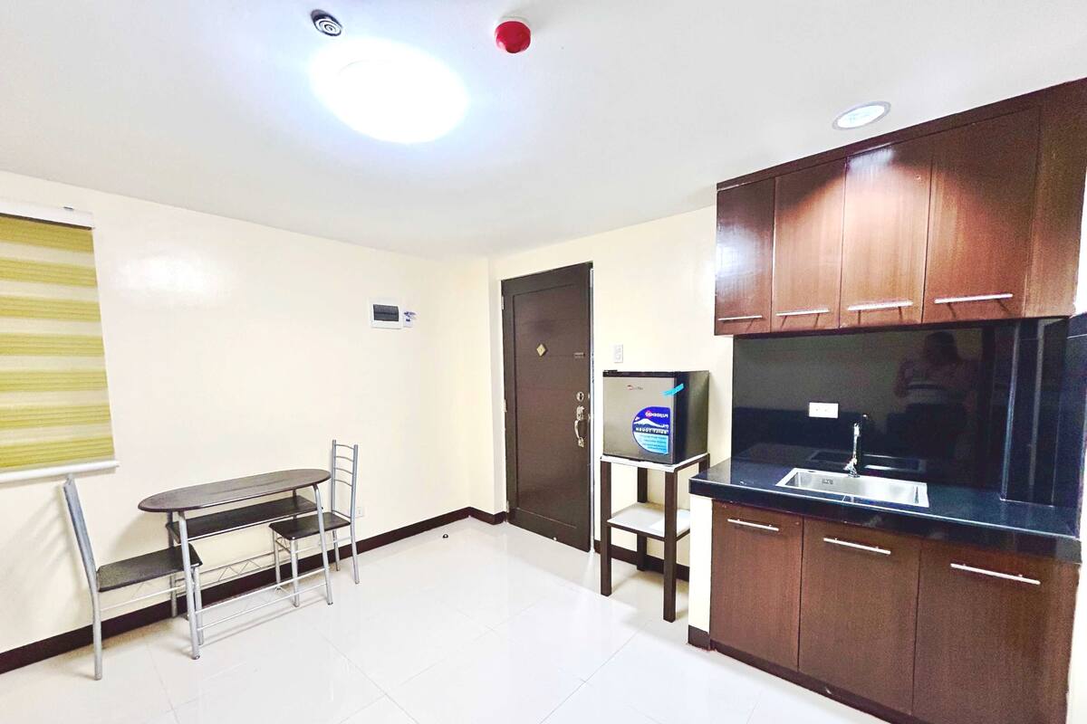 A small, well-lit kitchen with a refrigerator, a sink, and wooden cabinets.