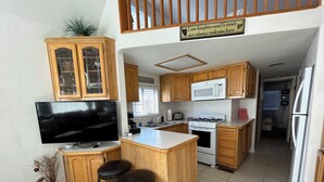 Une cuisine moderne avec des meubles en bois, un four à micro-ondes encastré, une cuisinière et un grand îlot central doté de tabourets.