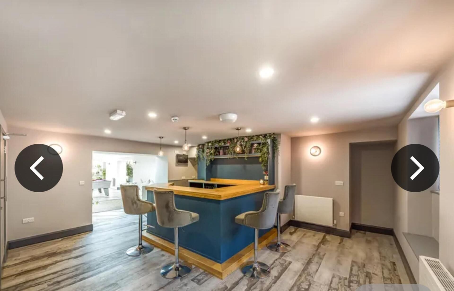 A modern kitchen with a central island, bar stools, and recessed lighting.