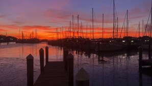 A marina at sunset with multiple boats docked.
