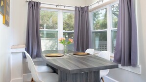 A dining area with a dark wood table, white chairs, and a vase with flowers.