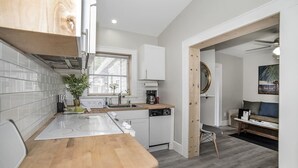 A modern kitchen with white cabinets, a wooden countertop, and a built-in dishwasher.
