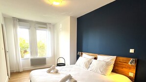 A bedroom with a large bed, a wooden headboard, and a view of greenery through the window.
