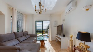 Sala de estar com sofá, televisão, luminária e objetos decorativos.