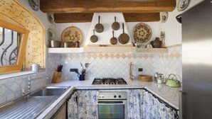 A kitchen with a gas stove, oven, and various utensils on the counter. - MANOR HOUSE (ARZACHENA LOC. CAPRICCIOLI)