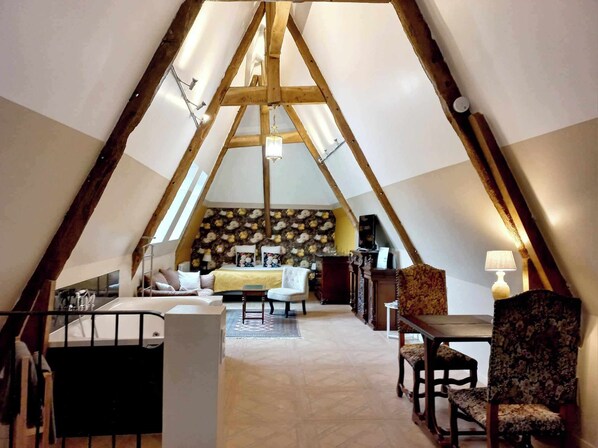 A cozy, triangular room with a bed, seating area, and a table. - Manoir de Barbotin (Ploërmel)