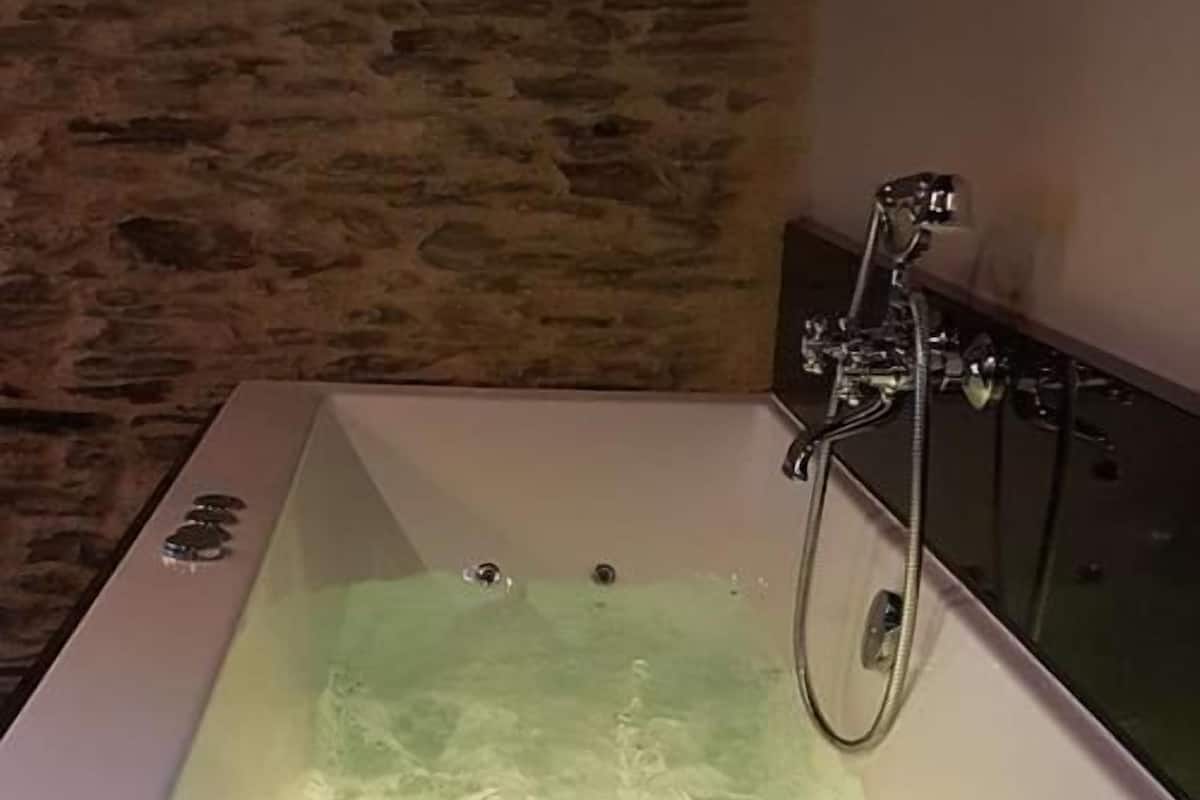 Uma banheira com água corrente, um chuveiro e uma torneira.
