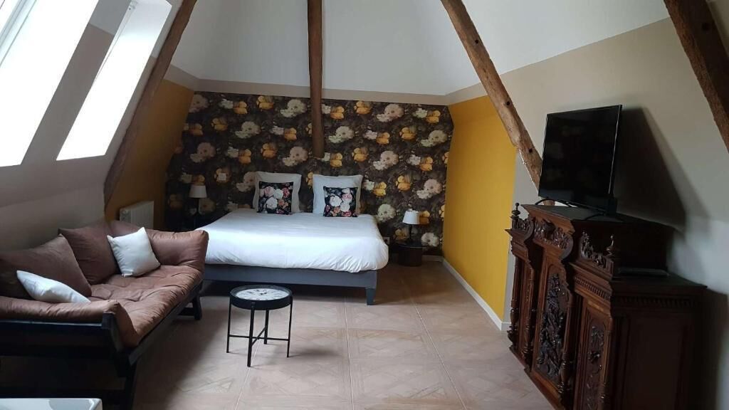 A bedroom with a bed, a sofa, a TV, and a wooden cabinet.