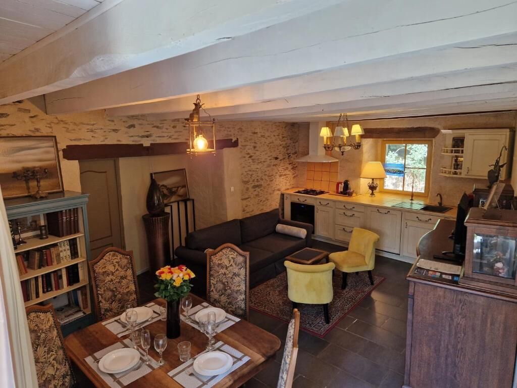 A spacious living area with a dining table set for four, a sofa, and a kitchen area with a stove and cabinets.