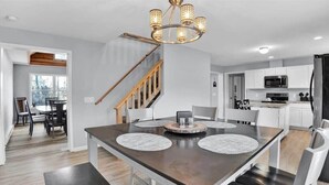 Une cuisine moderne avec des armoires blanches, un réfrigérateur noir et un escalier en bois.