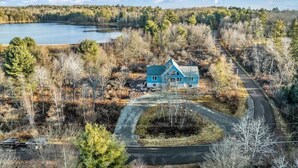 Une maison entourée d’arbres et bordée par un lac.