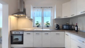 A modern kitchen with a built-in oven, a microwave, a coffee machine, and a wine bottle. - Villa Petar by Villas Guide (Buroli)