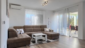 A modern living room with a sectional sofa, a coffee table, and a view to an outdoor patio. - Villa Petar by Villas Guide (Buroli)