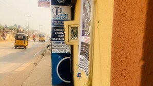 A roadside view with a hotel named 'Prince Palace' and a sign for 'POAM Errands Concept'. - Prince Palace Hotel (Lagos)