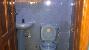 A small bathroom with a toilet, sink, and blue tiles. - Prince Palace Hotel (Lagos)
