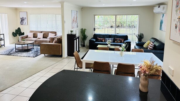 A spacious living area with a large dining table, two sofas, and a kitchen area. - Rest in Auckland City, Sylvia Park New Zealand (Auckland)