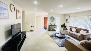 A living room with a TV, sofa, coffee table, and a bookshelf. - Rest in Auckland City, Sylvia Park New Zealand (Auckland)