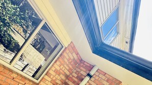 A corner of a building with a brick wall, a window, and a gutter. - Rest in Auckland City, Sylvia Park New Zealand (Auckland)