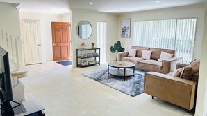 A spacious living room with a sofa, armchair, coffee table, and bookshelf. - Rest in Auckland City, Sylvia Park New Zealand (Auckland)