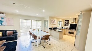 A modern kitchen with a central island, a dining area with a table and chairs, and a living area with a sofa and a coffee table. - Rest in Auckland City, Sylvia Park New Zealand (Auckland)