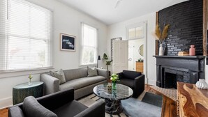 Een moderne woonkamer met een bank, fauteuils, een ronde salontafel en een open haard.