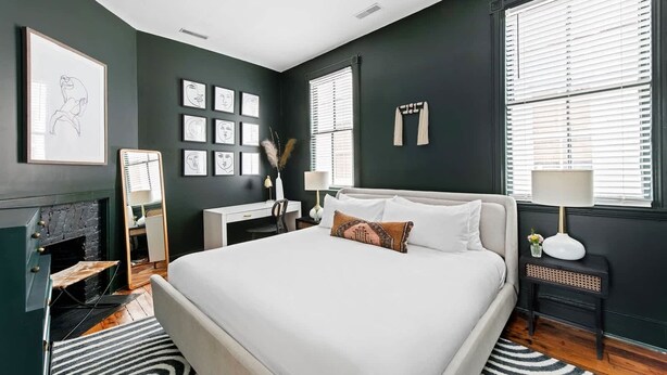 Een moderne slaapkamer met een groot bed, een bureau, een open haard en kunstwerken aan de muur.