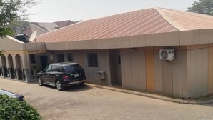 A building with a reception area, a parked black SUV, and a satellite dish on the roof. - Icon valley Hotel limited (Abuja)