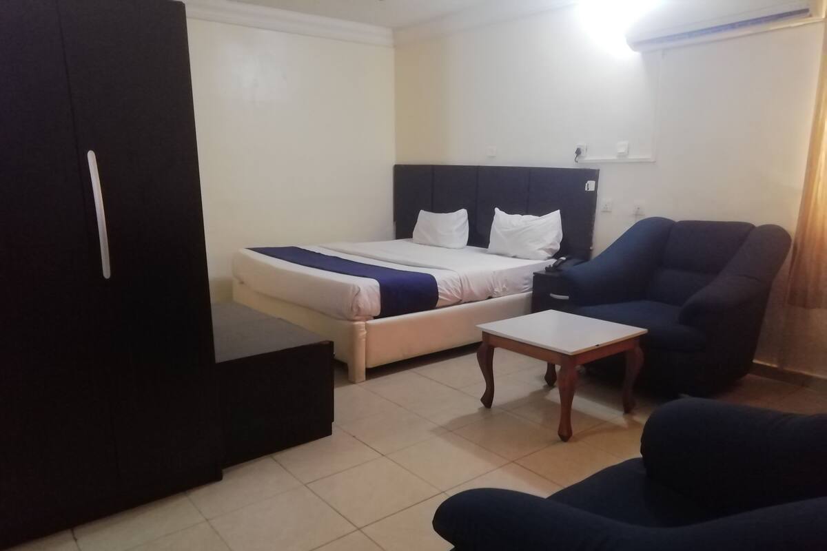 A bedroom with a bed, a nightstand, a chair, and a wardrobe.