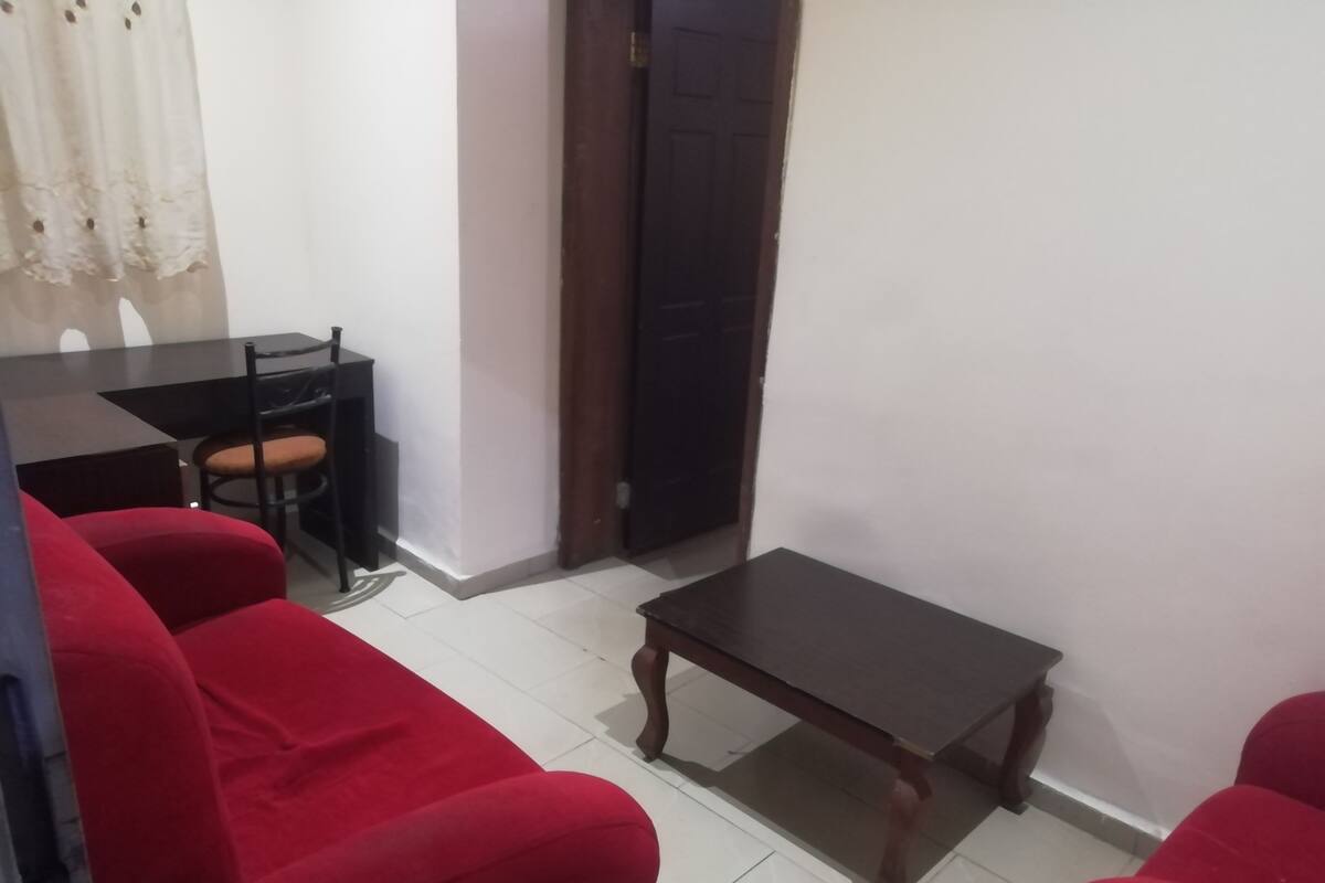 A room with a red sofa, a small wooden table, and a dining table with chairs.