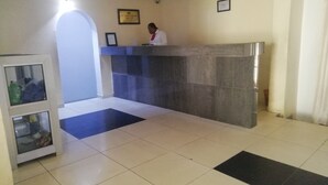 A reception area with a receptionist desk, a glass display cabinet, and a check-in counter. - Icon valley Hotel limited (Abuja)