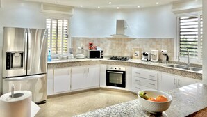 A modern kitchen with a stainless steel refrigerator, a built-in oven, a microwave, and a gas stove. - Bookwithclass-luxury Stay Pool Villa am Meer (Saly Portudal)