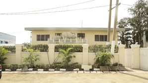 A two-story building with a balcony, surrounded by a low wall and potted plants. - Calbert lodge Abuja (Abuja)