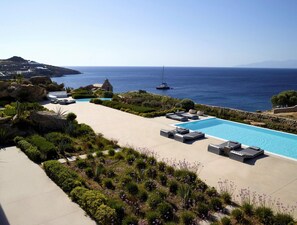 Un resort con piscina, sillones de descanso y vista al mar.