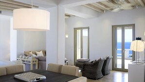 Ein modernes Wohnzimmer mit Essbereich, einem großen Fenster mit Meerblick und einem Deckenventilator.