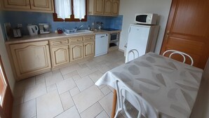 Une cuisine compacte dotée de meubles en bois, d’un évier, d’un four à micro-ondes et d’un coin repas avec une table et des chaises.