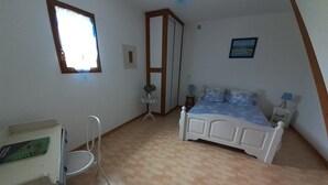 Une chambre à coucher avec un lit, une chaise, une petite table et une fenêtre.