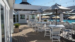 Un espace aménagé au bord de la piscine, avec des sièges d’extérieur, des parasols et des guirlandes lumineuses.