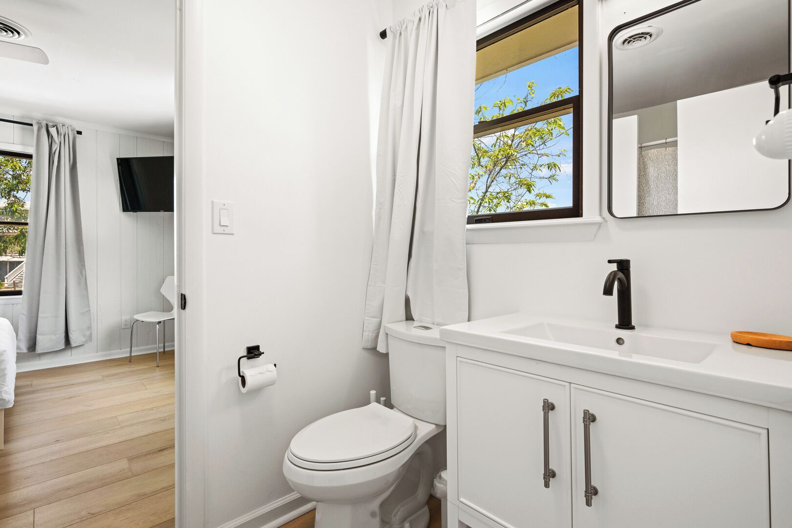 Et moderne badeværelse med toilet, vask og spejl.