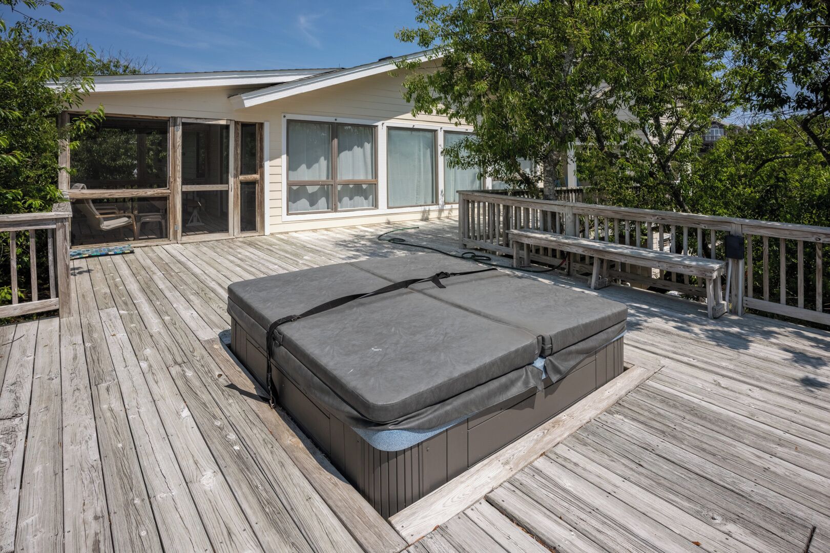 Une terrasse dotée d’un grand matelas d’extérieur gris et d’une rambarde en bois.