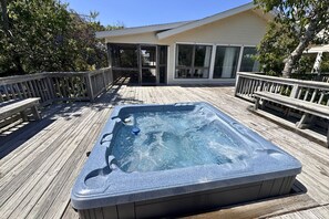 A hot tub on a wooden deck with a house in the background.