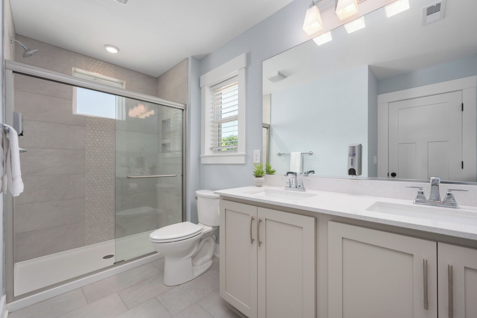 Une salle de bain moderne dotée d’une douche à parois de verre, de toilettes et d’un meuble-lavabo avec un grand miroir.