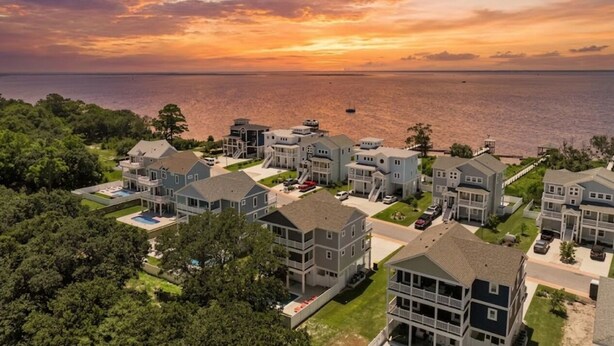 A coastal residential area with multiple two-story houses, a swimming pool, and a view of the ocean.