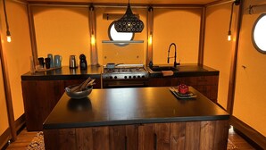 Una cocina compacta con una isla central, armarios de madera, estufa a gas y una lámpara colgante.